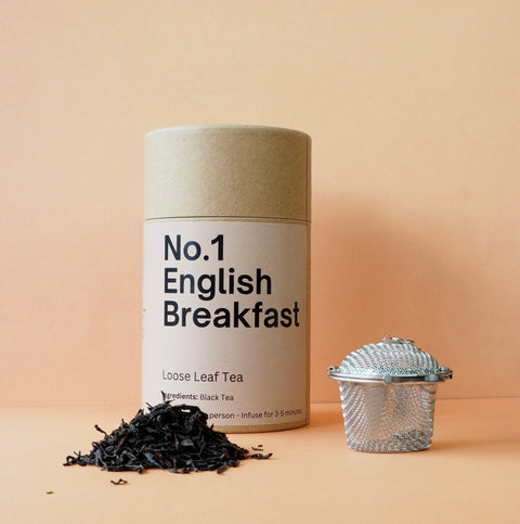 Tea canister labeled 'No. 1 English Breakfast' with loose tea leaves and a tea strainer on a beige background