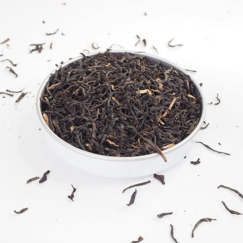 Assam Tea - Large loose tea leaves photographed in a dish showing the entangled leaves of different shades spilling over the sides - Assam tea is black and strong - this tea is available from Teaspoon Tea Co