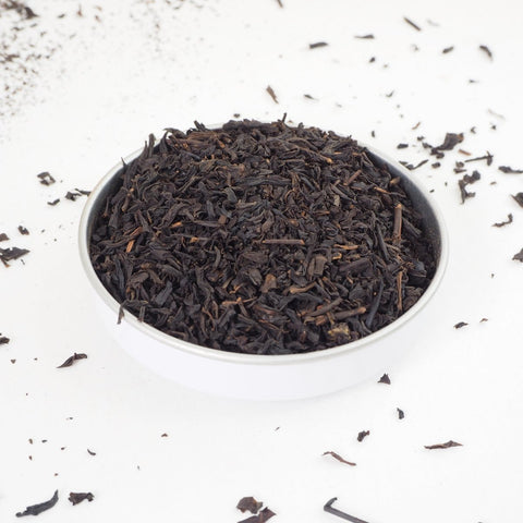 Lapsang Souchong Loose Leaf Tea, shown in a small bowl. This is a Smokey tea from Teaspoon Tea Co. Lapsang Souchong has large rolled leaves that taste smokey and rich. This is a quality loose leaf tea.