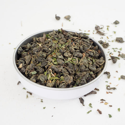 Gunpowder green tea is combined with cut peppermint to produce Moroccan Mint Green Loose Leaf Tea from Teaspoon Tea Co.  The rolled leaf of the gunpowder green tea can be seen here with brighter peppermint leaves also visible.  This is a green tea that tastes good.