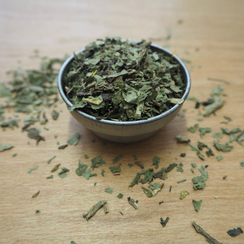 Dandelion tea in a metal bowl on a wooden surface