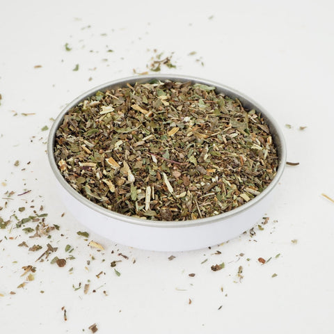 Peppermint Tea from Teaspoon Tea Co is shown in a small dish. Green cut Peppermint leaves of different shades of green, light green and dark green. Peppermint tea is a caffeine-free herbal tea that tastes fresh and sweet