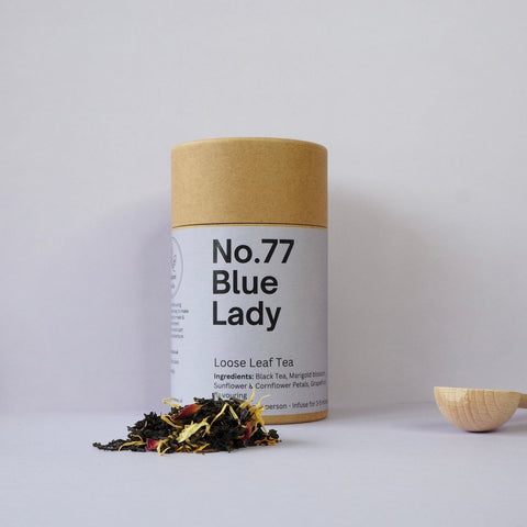 A cylindrical cardboard container labeled 'No.77 Blue Lady Loose Leaf Tea'