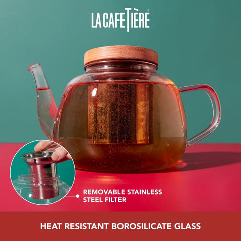 Glass teapot with wooden lid on a red surface, featuring La Cafétière branding.