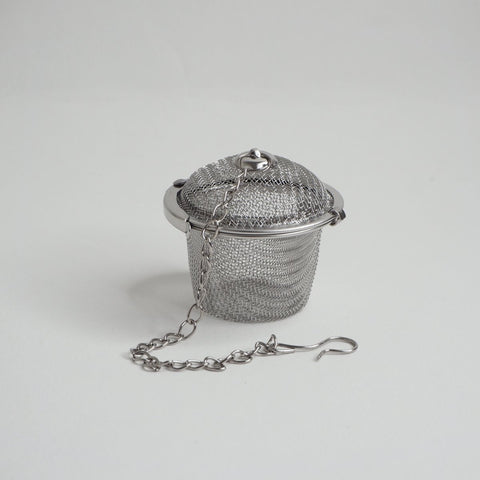 A stainless steel tea basket infuser with a lid and a chain handle