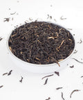 Assam Tea - Large loose tea leaves photographed in a dish showing the entangled leaves of different shades spilling over the sides - Assam tea is black and strong - this tea is available from Teaspoon Tea Co
