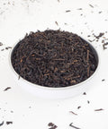 Lapsang Souchong Loose Leaf Tea, shown in a small bowl.  This is a Smokey tea from Teaspoon Tea Co. Lapsang Souchong has large rolled leaves that taste smokey and rich.  This is a quality loose leaf tea.