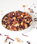 A bowl of spiced apple loose fruit tea showing the dried fruit, scattered on a white background