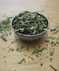 Dandelion tea in a metal bowl on a wooden surface