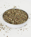 Peppermint Tea from Teaspoon Tea Co is shown in a small dish. Green cut Peppermint leaves of different shades of green, light green and dark green. Peppermint tea is a caffeine-free herbal tea that tastes fresh and sweet
