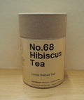 Cardboard container of No.68 Hibiscus Tea on a wooden surface with a beige background