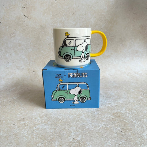 Mug with cartoon design on a box labeled 'Peanuts' on a beige background