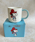 Mug with snoopy on a blue box featuring 'Peanuts' branding.