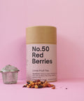 A cylindrical container labeled 'No.50 Red Berries' with a loose fruit tea mixture displayed in front, on a pink background.