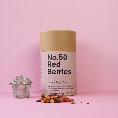 A cylindrical container labeled 'No.50 Red Berries' with a loose fruit tea mixture displayed in front, on a pink background.