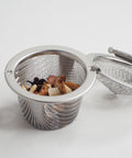 stainless steel tea infuser with tea inside and the lid open