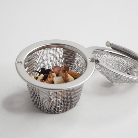 stainless steel tea infuser with tea inside and the lid open