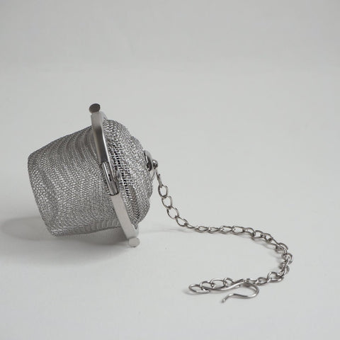 stainless steel infser basket on its side with chain