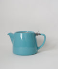 Turquoise teapot with a metal lid on a white background